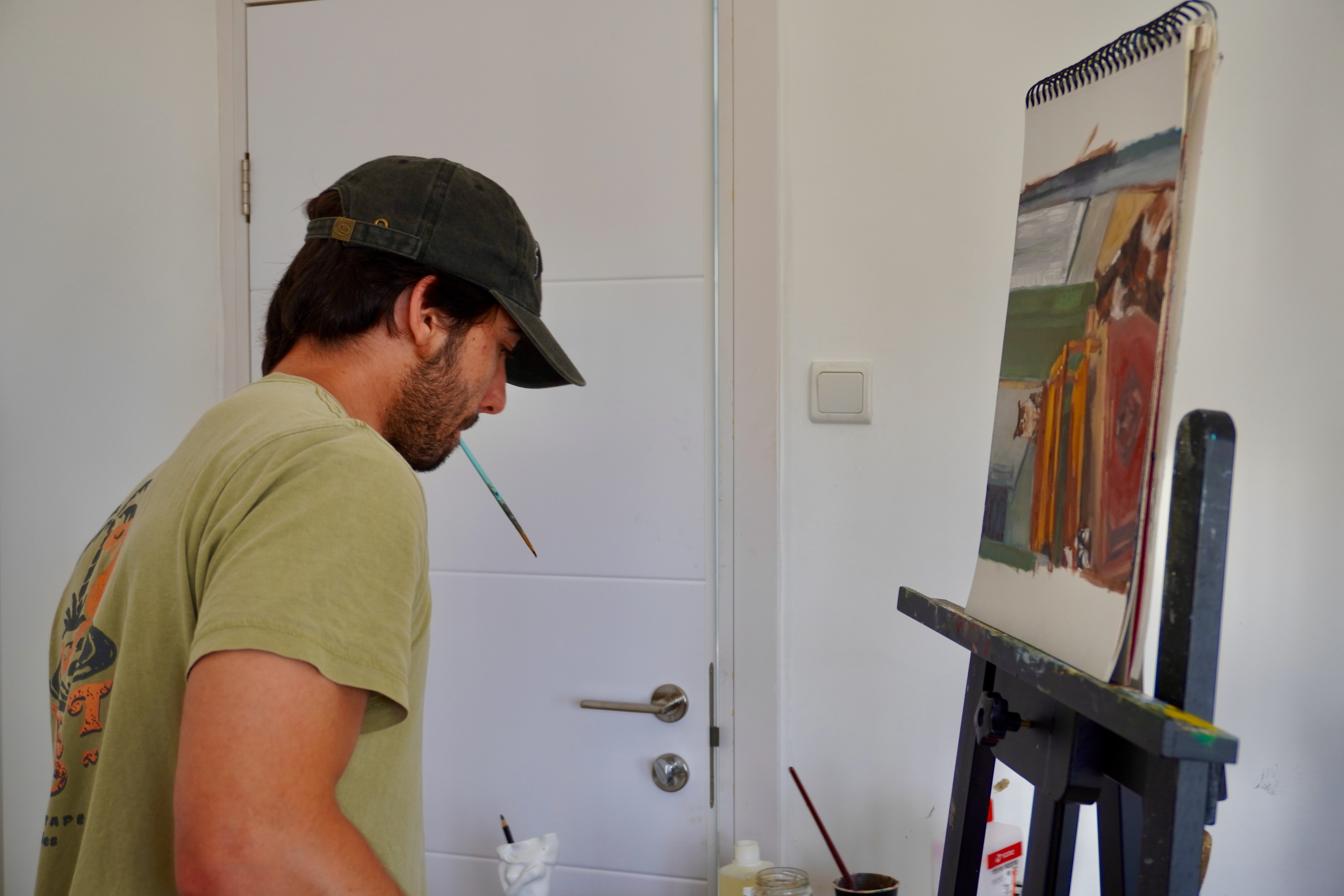 Yoav Mendelson painting at an easel in his workspace.